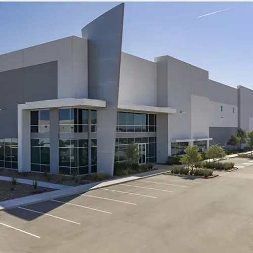 A modern warehouse with a large parking lot sits prominently in Goodyear Arizona landscaping surrounds the buildings base