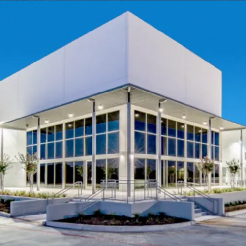 A modern building with large windows dominates the scene in Grand Prairie Texas Its facade features concrete steps and
