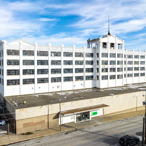 A dilapidated industrial building dominates the scene in Kansas City featuring numerous large windows and a flat roof