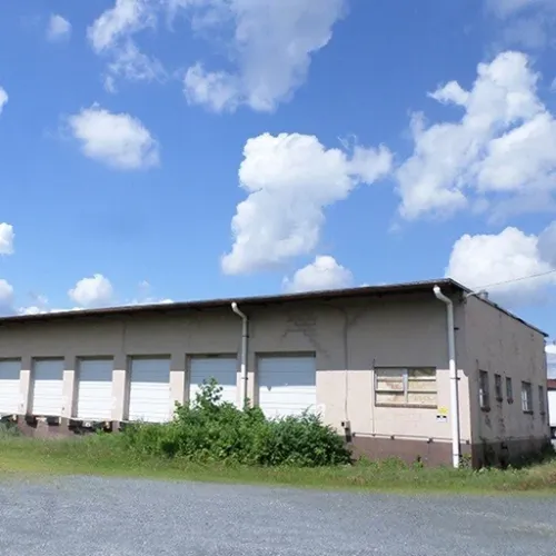 A weathered gray industrial building stands in Philadelphia Pennsylvania with peeling white doors and boarded windows